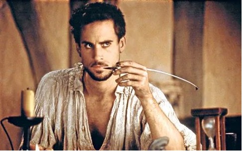Joseph Fiennes as William Shakespeare in the film "Shakespeare in Love". Fiennes as Shakespeare is starting in a contemplative manner with a quill near his mouth.